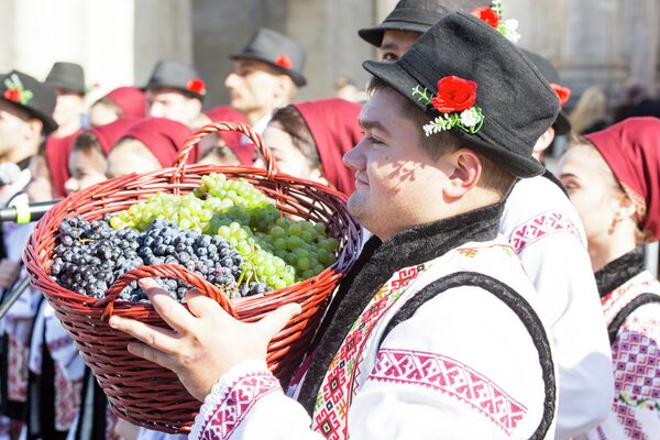 Мужчина в национальном костюме несет корзину с виноградом - Sputnik Молдова