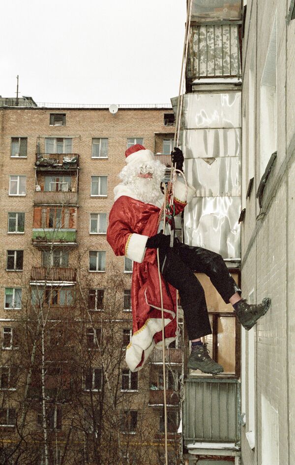 Профессиональный скалолаз в роли Деда Мороза спускается на тросе по стене дома - Sputnik Moldova