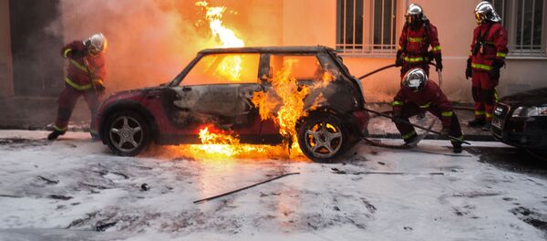 Сотрудники противопожарной службы тушат горящий автомобиль во время акции протеста участников движения автомобилистов желтые жилеты в районе Триумфальной арки в Париже - Sputnik Молдова