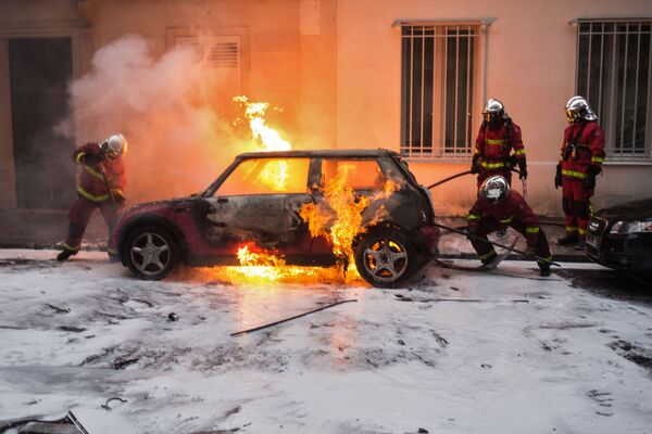 Сотрудники противопожарной службы тушат горящий автомобиль во время акции протеста участников движения автомобилистов желтые жилеты в районе Триумфальной арки в Париже - Sputnik Молдова