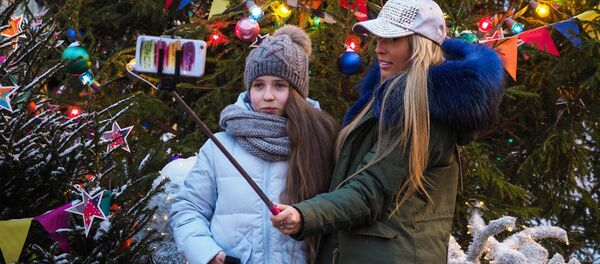 Taking selfies near the Christmas tree at the GUM-Fair on the Red Square in Moscow - Sputnik Молдова