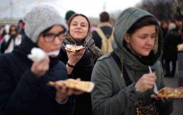 Девушки едят блины во время масленичных гуляний в Парке Горького в Москве - Sputnik Молдова