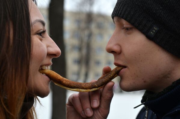 Молодые люди едят блин на празднике Широкая Масленица в Казани - Sputnik Молдова