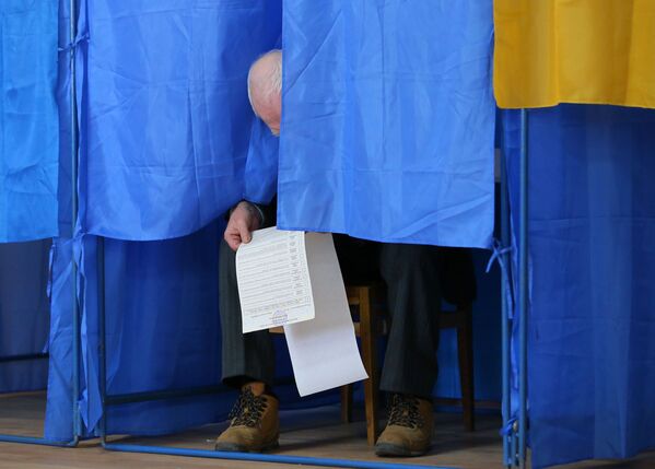 Мужчина изучает бюллетень в кабинке для голосования на президентских выборах на одном из избирательных участков Киева - Sputnik Moldova-România