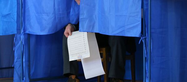 Мужчина изучает бюллетень в кабинке для голосования на президентских выборах на одном из избирательных участков Киева - Sputnik Moldova-România