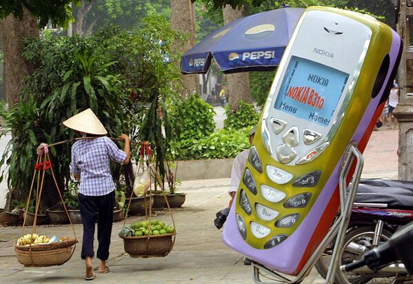 Продавец фруктов проходит мимо магазина мобильных телефонов в Ханое, Вьетнам. 2002 год - Sputnik Молдова