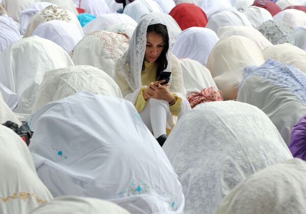 Мусульманка с мобильным телефоном среди молящихся во время празднования Ид аль-адха в Джакарте - Sputnik Молдова