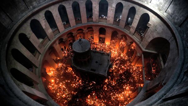 Christian Orthodox worshipers hold up candles lit from the Holy Fire as thousands gather in the Church of the Holy Sepulchre in Jerusalem’s Old City - Sputnik Moldova-România