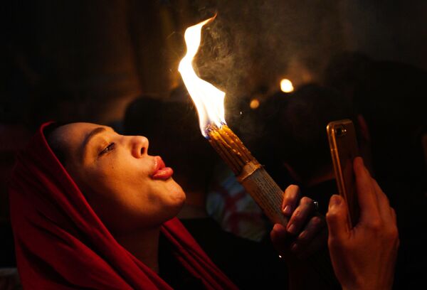 Женщина празднует схождение Благодатного огня в храме Гроба Господня - Sputnik Молдова