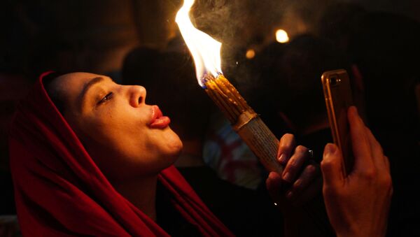 Женщина празднует схождение Благодатного огня в храме Гроба Господня - Sputnik Moldova-România