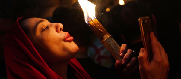 Женщина празднует схождение Благодатного огня в храме Гроба Господня - Sputnik Moldova-România