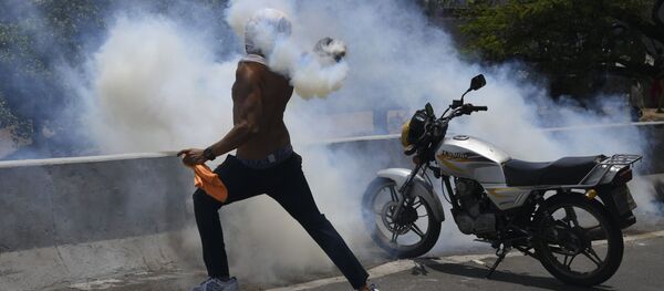 Протестующий кидает бутылку со слезоточивым газом во время столкновения с Национальной гвардией Венесуэлы в Альтамире, районе Каракаса - Sputnik Moldova-România