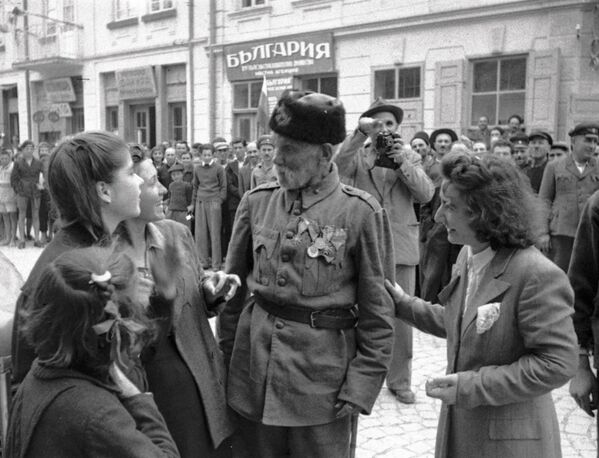 Un veteran al războiului cu Turcia discută cu niște domnișoare într-un oraș din Bulgaria eliberat de Armata Roșie de sub ocupația fascistă, anul 1944 - Sputnik Moldova