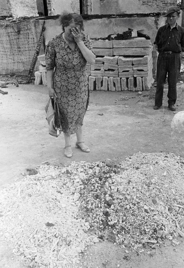 O femeie plângând lângă rămășițele pământești ale oamenilor arși de vii în lagărul de exterminare Majdanek - Sputnik Moldova