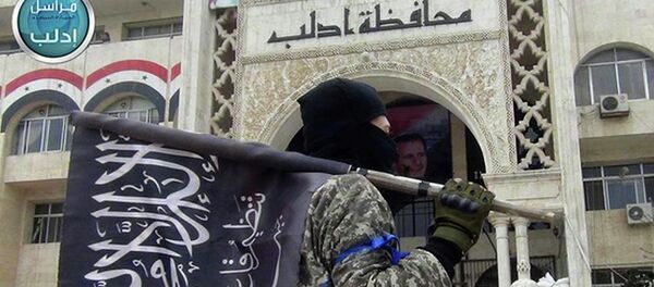 A fighter from Syria's al-Qaida-linked Nusra Front holds his group flag as he stands in front of the governor building in Idlib province, north Syria. A fighter from Syria's al-Qaida-linked Nusra Front holds his group flag as he stands in front of the governor building in Idlib province, north Syria. - Sputnik Moldova-România