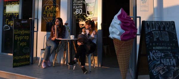 Девушки сидят за столиком в уличном кафе.
 - Sputnik Молдова