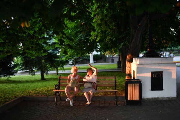 Отдыхающие сидят на скамейке в парке в Севастополе в Крыму - Sputnik Moldova-România