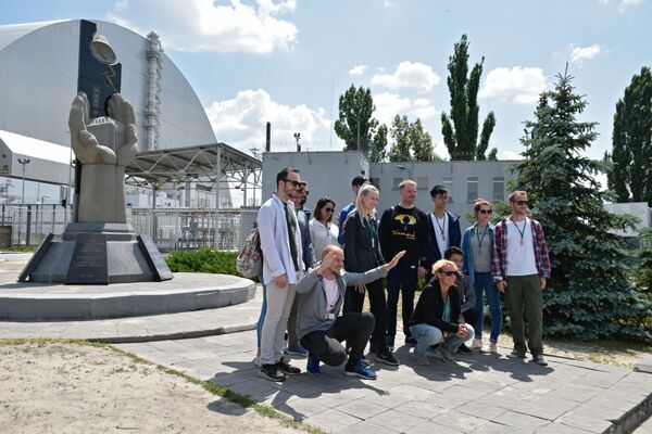 Туристы фотографируются возле памятника ликвидаторам аварии на ЧАЭС  во время экскурсии в зону отчуждения в городе Чернобыль - Sputnik Moldova-România
