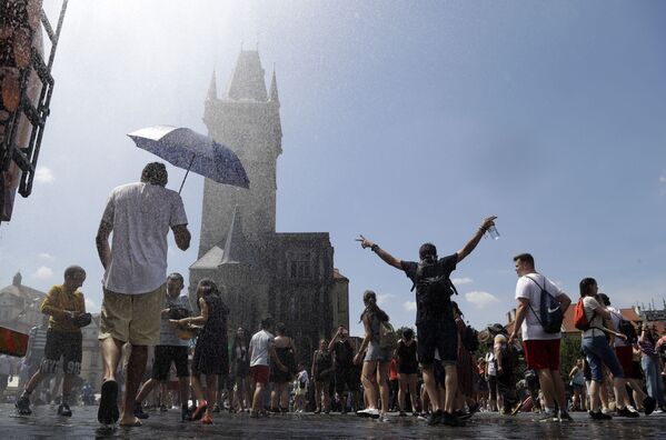 Люди охлаждаются под струей воды в жаркий и летний день на Староместской площади в Праге, Чехия - Sputnik Moldova-România