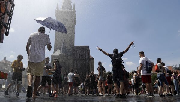 Люди охлаждаются под струей воды в жаркий и летний день на Староместской площади в Праге, Чехия - Sputnik Молдова