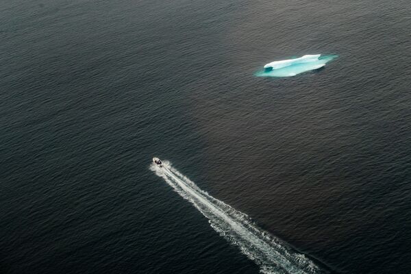 Катер проходит мимо айсберга в открытом океане возле Тасиилака, Гренландия - Sputnik Moldova-România