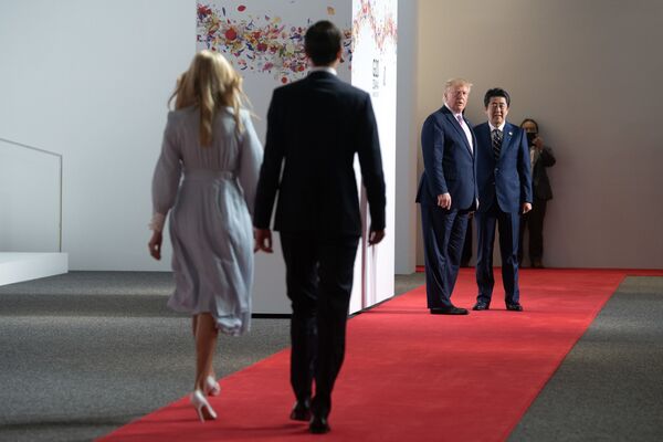 Consilierul preşedintelui SUA Ivanka Trump şi consilierul principal Jared Kushner merg spre preşedintele SUA, Donald Trump, şi prim-ministrul Japoniei, Shinzo Abe, pentru a li se alătura sesiunii de fotografiere din prima zi a summit-ului G20 d ela Osaka, pe 28 iunie 2019 - Sputnik Moldova-România