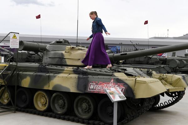 Посетительница форума рассматривает образец танка Т-80Б на статической площадке полигона Алабино - Sputnik Молдова