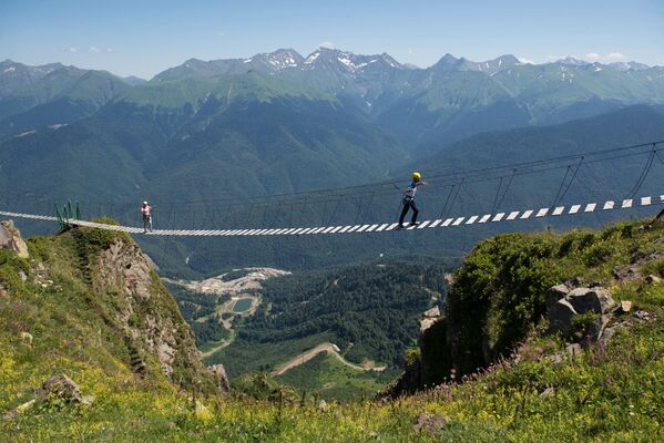 Туристы идут по подвесному пешеходному мосту над ущельем на горнолыжном курорте Роза Хутор в Сочи - Sputnik Moldova-România