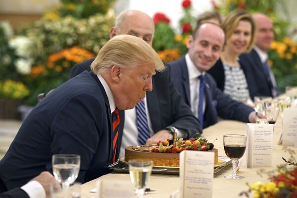 Președintele american Donald Trump suflă  lumânarea  de pe tortă de sa ziua de naștere în timpul unei întâlniri cu premierul din Singapore, Lee Xianglong - Sputnik Moldova