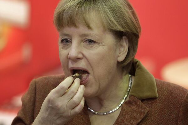 Cancelarul german Angela Merkel în timp ce mănâncă o bucată de ciocolată - Sputnik Moldova