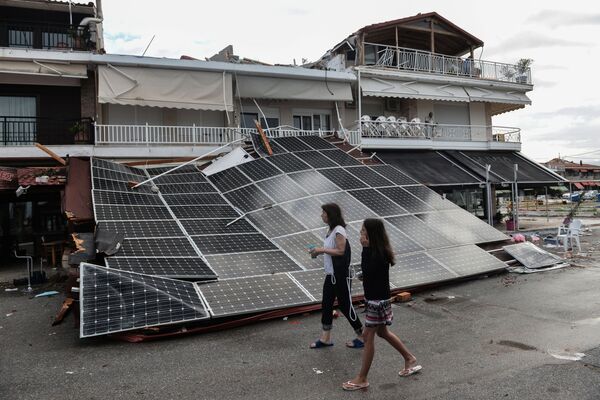 Turiștii trec pe lângă un acoperiș panouri solare, prăbușit în Nea Plagia după o furtună pe Halkidiki, Grecia de Nord - Sputnik Moldova-România