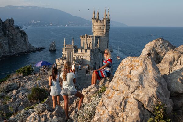 Отдыхающие фотографируются возле замка Ласточкино гнездо на береговой скале в поселке Гаспра в Крыму - Sputnik Молдова