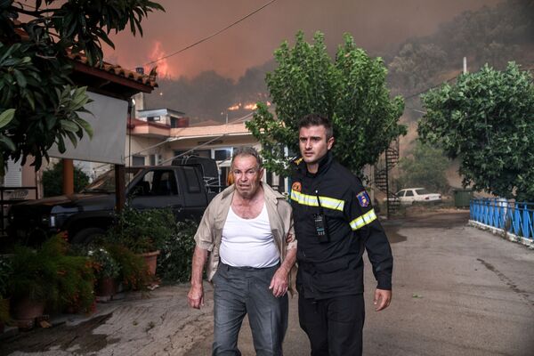 Пожарный помогает местному жителю в деревне Кондодеспоти во время лестных пожаров на греческом острове Эвбея - Sputnik Moldova-România