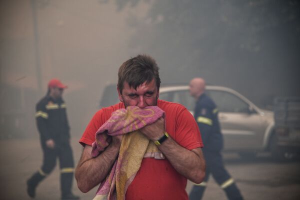 Мужчина закрывает лицо полотенцем во время лесных пожаров на острове Эвия, Греция - Sputnik Moldova-România