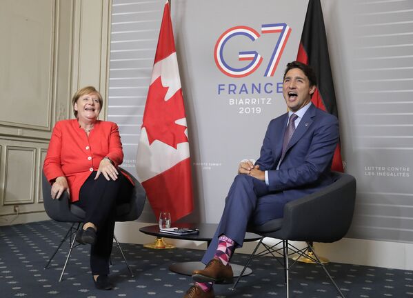 Cancelarul german Angela Merkel și premierul canadian Justin Trudeau reacționează în timp ce se întâlnesc în a doua zi a summitului G-7 de la Biarritz, Franța, duminică, 25 august 2019. - Sputnik Moldova-România