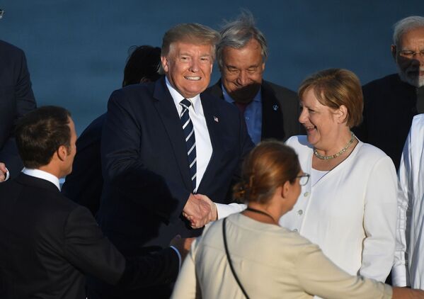 Președintele francez, Emmanuel Macron, reacționează în timp ce președintele american Donald Trump și cancelarul german Angela Merkel își strâng mâinile în timpul sesiunii de fotografie de familie la summitul G7 de la Biarritz, Franța, 25 august 2019 - Sputnik Moldova