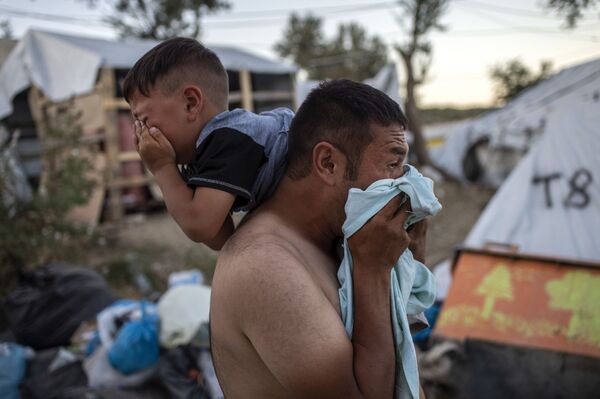 Мужчина с ребенком во время столкновений возле лагеря беженцев Мория на греческом острове Лесбос - Sputnik Молдова