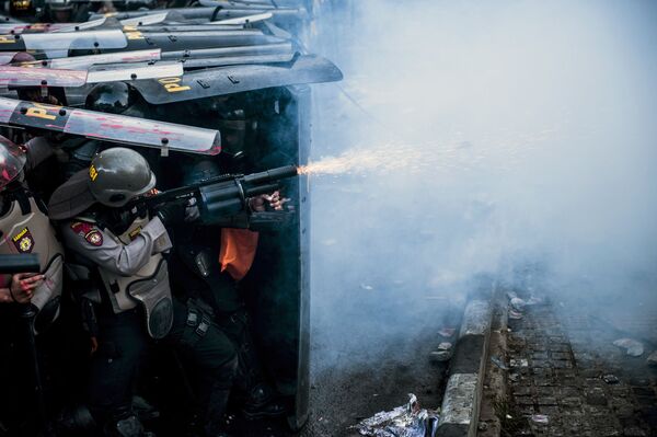Полицейский применяет слезоточивый газ во время столкновения со студенческими демонстрантами в Бандунге, Индонезия - Sputnik Молдова