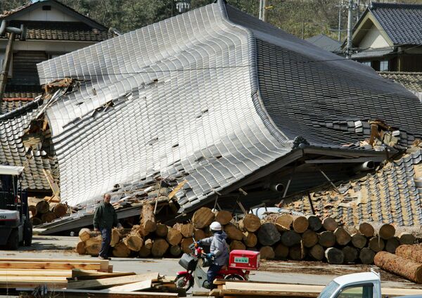 Японский почтальон проезжает мимо зданий в Вадзиме, пострадавших в результате. землетрясения - Sputnik Молдова