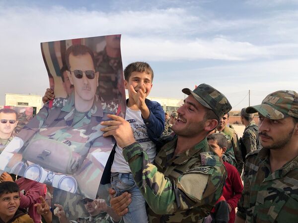 Дети и военнослужащие с плакатами с портретом президента Сирии Башара Асада в освобожденном сирийской правительственной армией городе Манбидж в Сирии - Sputnik Молдова