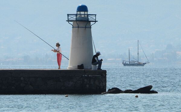 Отдыхающие ловят рыбу возле маяка в заливе Нотиос-Эввоикос Эгейского моря - Sputnik Молдова