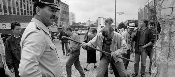 На фото сверху мужчина пытается разбить часть Берлинской стены на улице Markgrafen Strasse/Rudi-Dutschke Strasse 2 июня 1990 года, и внизу - то же место 30 октября 2019 года, Германия На фото сверху мужчина пытается разбить часть Берлинской стены на улице Markgrafen Strasse/Rudi-Dutschke Strasse 2 июня 1990 года, и внизу - то же место 30 октября 2019 года, Германия - Sputnik Moldova-România