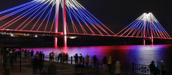 Окрашенный в цвета российского государственного флага Виноградовский пешеходный мост во время светомузыкального спектакля Сердце Сибири в рамках праздничной программы в День народного единства в Красноярске - Sputnik Молдова