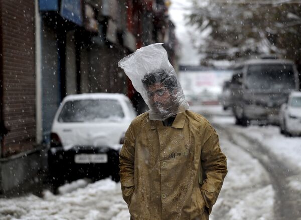 Мужчина прикрывает голову полиэтиленовым пакетом во время снегопада в Сринагаре, Кашмир - Sputnik Молдова