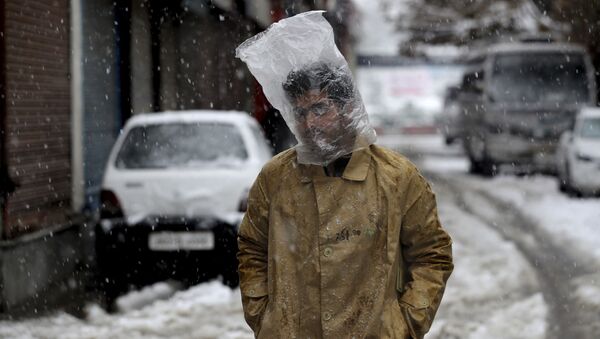 Мужчина прикрывает голову полиэтиленовым пакетом во время снегопада в Сринагаре, Кашмир - Sputnik Moldova-România