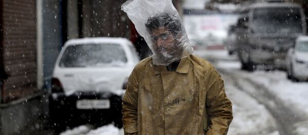 Мужчина прикрывает голову полиэтиленовым пакетом во время снегопада в Сринагаре, Кашмир Мужчина прикрывает голову полиэтиленовым пакетом во время снегопада в Сринагаре, Кашмир - Sputnik Moldova-România