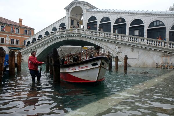 Человек привязывает лодку к мосту во время наводнения в Венеции - Sputnik Moldova-România