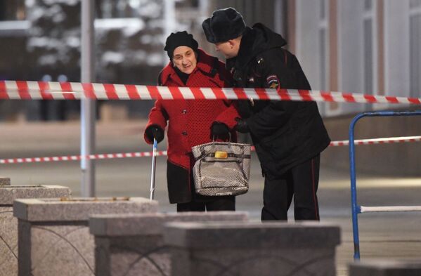 Сотрудник полиции помогает женщине пройти в зоне оцепления недалеко от здания ФСБ на Лубянской площади в Москве, где произошла стрельба - Sputnik Молдова