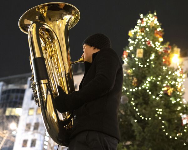 Музыкант духового оркестра Rudersdorf Music Society играет на трубе на рождественском базаре в Вене - Sputnik Молдова