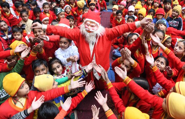 Девушка в костюме Санта-Клауса раздает подарки детям в Индии  - Sputnik Молдова